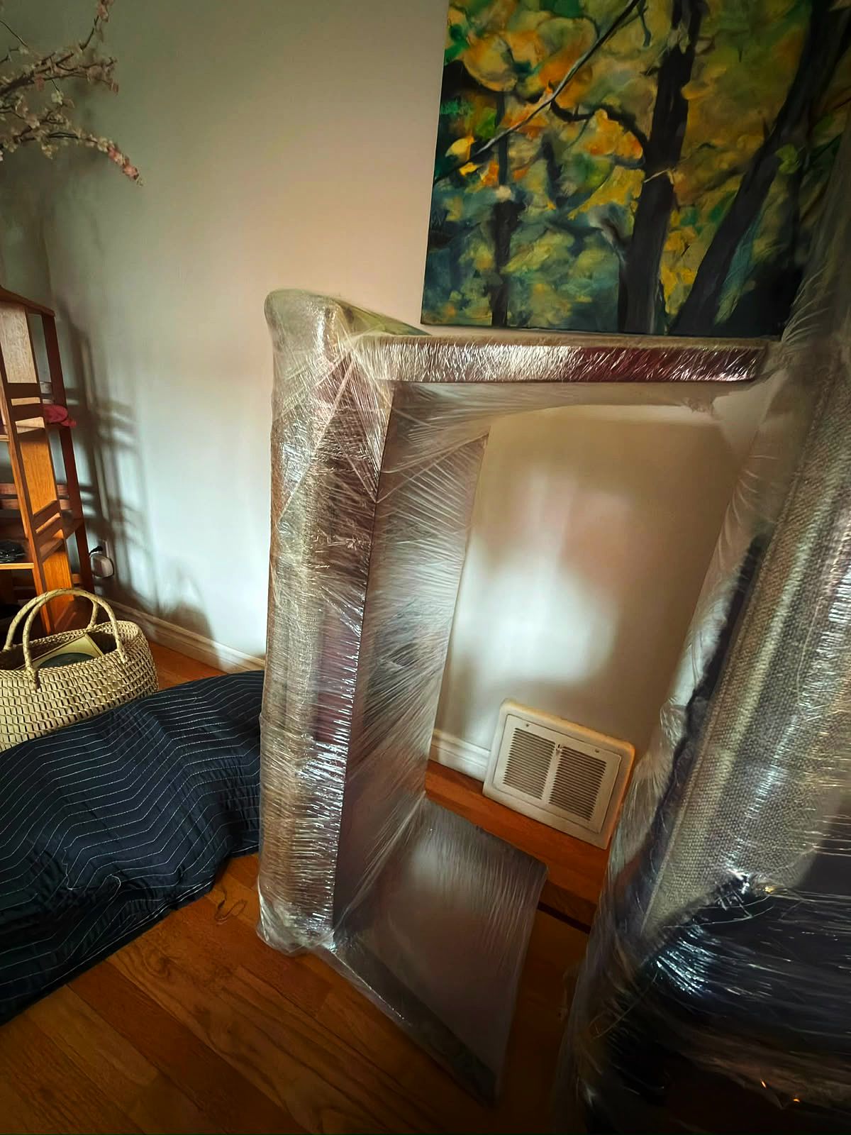 Console table frame wrapped in stretch film, resting on a moving blanket